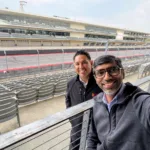 Joseph L. Soliz and a colleague taking a selfie in the grandstands of a motorsport racetrack