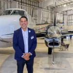 Joseph L. Soliz standing beside a turboprop aircraft in an airport hangar