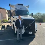 Joseph L. Soliz standing in front of an autonomous Volvo semi truck with roof-mounted sensors